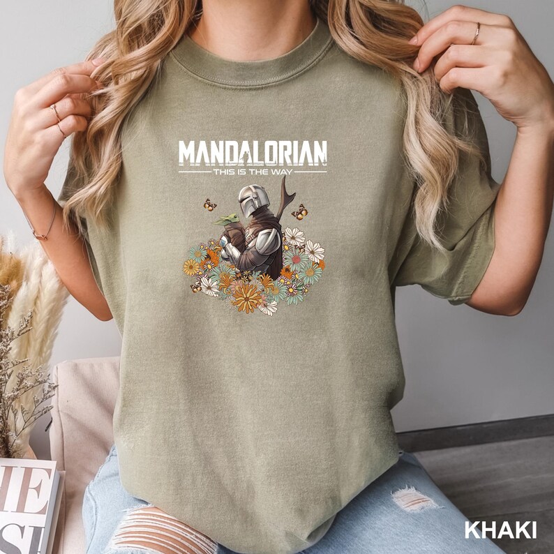 A person wearing a green t-shirt with a graphic of a character from the Mandalorian television series.