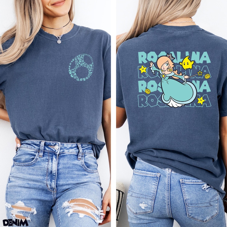 May include: A navy blue short-sleeve t-shirt featuring a small light blue circular graphic on the front left chest. The back displays a large graphic of the character Rosalina, a yellow star, and the text ROSALINA repeated in a light blue font.