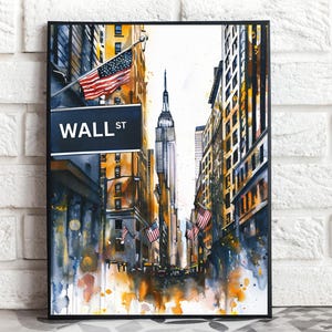 May include: Watercolour painting of Wall Street in New York City, featuring the Empire State Building and American flags. The artwork is framed in black and set against a white brick wall.