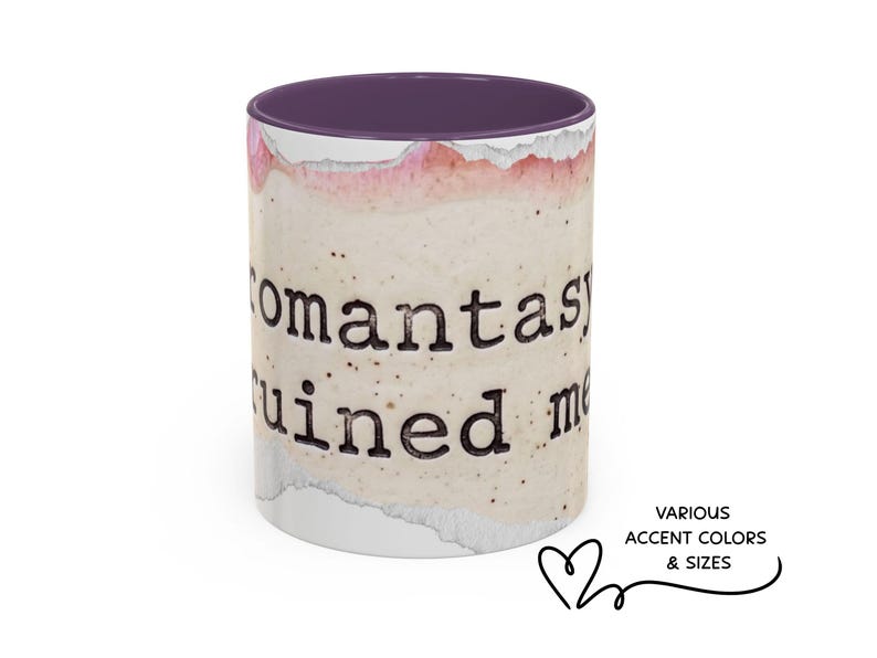 May include: A ceramic mug with a purple interior and a speckled, off-white exterior. The mug features the text "romantasy ruined me" in a black, typewriter-style font. The design includes watercolor-style pink and white accents.