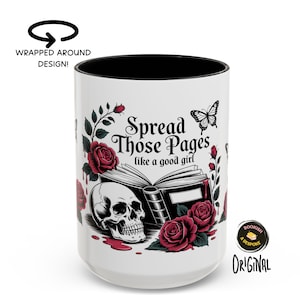 May include: White ceramic mug with a black interior, featuring a design with a skull, roses, and the text "Spread Those Pages like a good girl." A butterfly graphic is also included. The mug has a wrapped-around design.