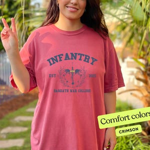 Puede incluir: Camiseta roja carmes&iacute; con un estampado gr&aacute;fico negro que dice "INFANTRY EST 2023 BASSGIATH WAR COLLEGE".