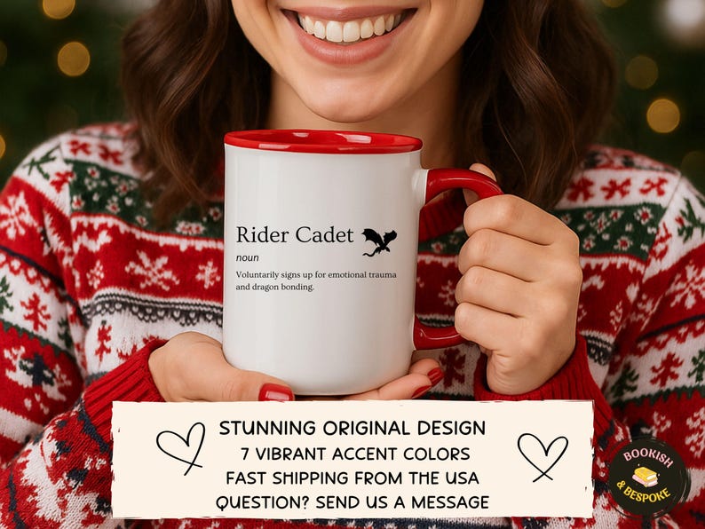 May include: A white ceramic mug with a red interior and handle, featuring the text "Rider Cadet" and a dragon silhouette. The mug also has the definition of "Rider Cadet". The mug is held by a person wearing a red and white sweater.