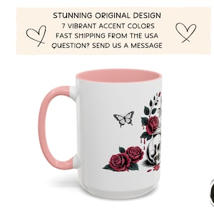 May include: White ceramic mug with a pink handle and interior. The mug features a design of a skull, roses, and a butterfly. The text on the mug reads "STUNNING ORIGINAL DESIGN" and "7 VIBRANT ACCENT COLORS".