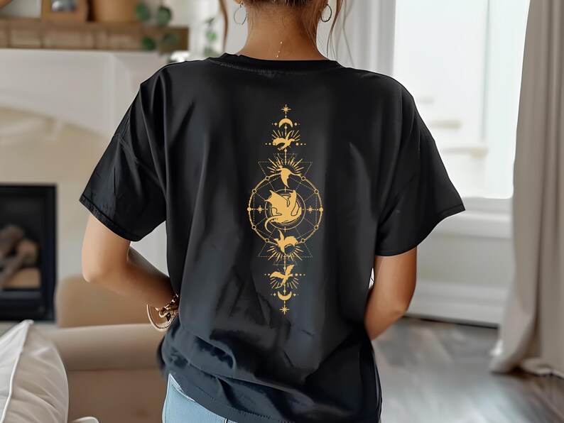 Puede incluir: Camiseta negra con un gr&aacute;fico dorado de un drag&oacute;n en un c&iacute;rculo con estrellas y lunas. El drag&oacute;n est&aacute; rodeado por un dise&ntilde;o geom&eacute;trico.