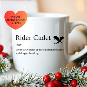 May include: White ceramic mug with the text "Rider Cadet" and a black dragon silhouette. The mug also features the definition of "Rider Cadet". A heart-shaped graphic indicates various accent colors and sizes.