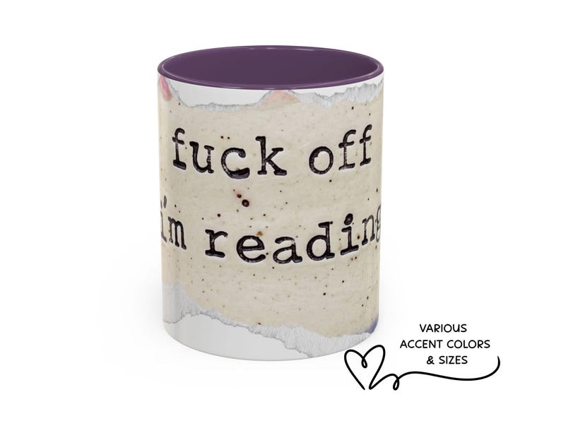 K&ouml;nnte beinhalten: Ein Keramikbecher mit violettem Innenraum und Rand, der eine beige, gesprenkelte, papierartige Textur aufweist. Der Text "fuck off i'm reading" ist in einer schwarzen Schriftart im Schreibmaschinenstil auf die Oberfl&auml;che gedruckt.