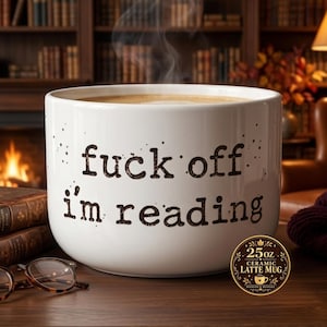 K&ouml;nnte beinhalten: Ein wei&szlig;er 710 ml Keramik-Latte-Becher mit schwarzem Text, der "fuck off i'm reading" in einer Schreibmaschinen-Schriftart zeigt. Der Becher hat eine breite, zylindrische Form und enth&auml;lt ein dampfendes Getr&auml;nk.