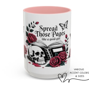 May include: White ceramic mug with a pink interior, featuring a skull, roses, and the text "Spread Those Pages like a good girl." A butterfly and book illustrations complete the design. Available in various accent colors and sizes.