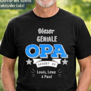 May include: A black short-sleeved t-shirt featuring white and blue text that reads "Dieser GENIALE OPA GEHÖRT ZU Louis, Lena & Paul". The design includes two small stars and is customizable with names. The shirt is worn with blue denim jeans.