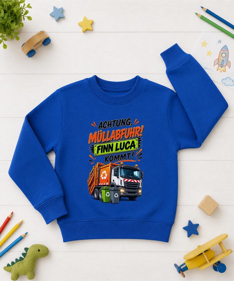 May include: A royal blue long-sleeve sweatshirt featuring a graphic of an orange garbage truck with two trash bins. The text reads "ACHTUNG M&Uuml;LLABFUHR! FINN LUCA KOMMT!" in orange, black, and white lettering above the truck illustration.