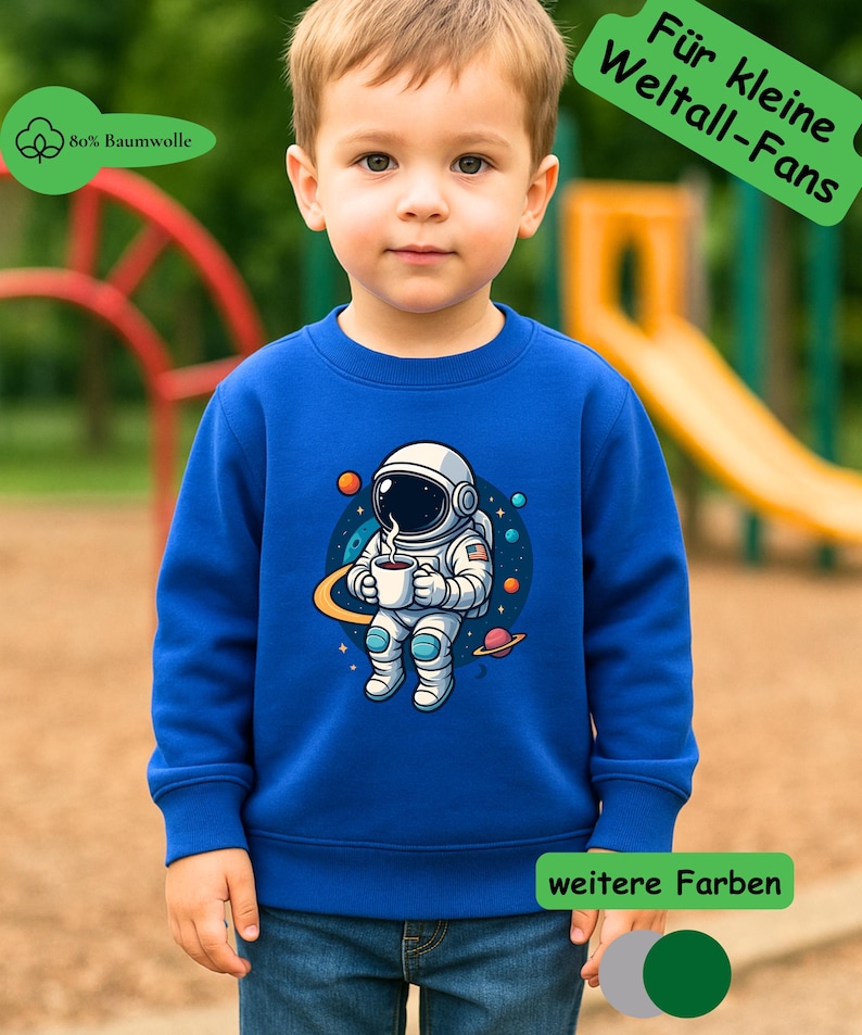 May include: A royal blue long-sleeve sweatshirt featuring a graphic of an astronaut holding a steaming mug in space, surrounded by planets and stars. The garment includes text labels reading 80% Baumwolle, F&uuml;r kleine Weltall-Fans, and weitere Farben.