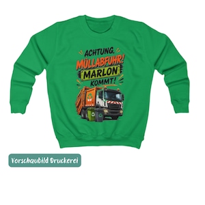 May include: A bright green long-sleeve sweatshirt featuring a graphic of an orange and white garbage truck with two trash bins. The text reads "ACHTUNG, M&Uuml;LLABFUHR! MARLON KOMMT!" in black and orange lettering above the truck illustration.