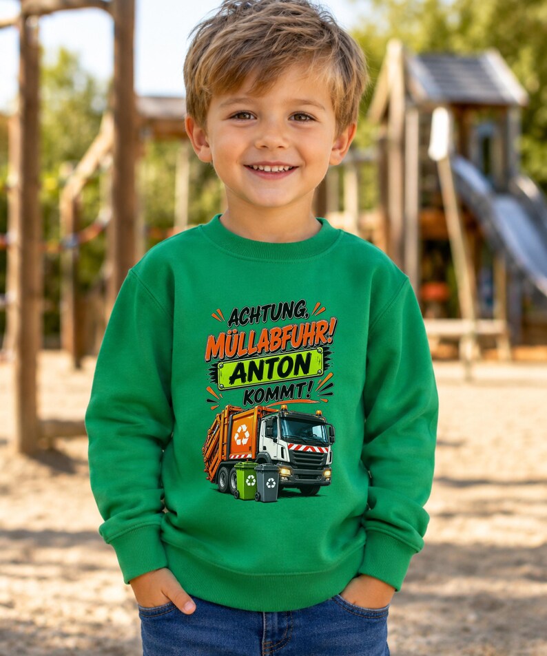May include: A bright green long-sleeve sweatshirt featuring a graphic print of an orange and white garbage truck with two small trash bins. The text reads ACHTUNG, M&Uuml;LLABFUHR! ANTON KOMMT! in orange, black, and white lettering on the front.