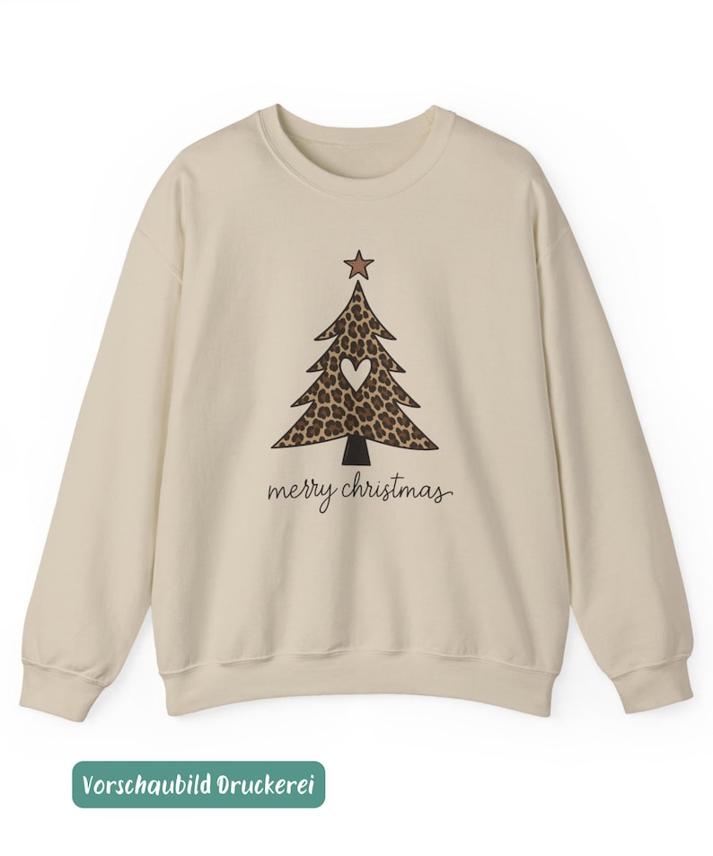 May include: A beige crewneck sweatshirt featuring a graphic of a Christmas tree with a brown leopard print pattern, a white heart in the center, and a brown star on top. The text merry christmas is printed in black cursive script below the tree.
