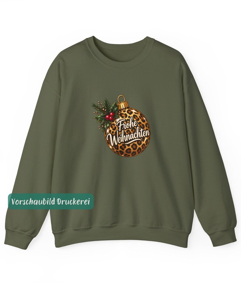 May include: An olive green crewneck sweatshirt featuring a central graphic of a round Christmas ornament with a leopard print pattern. The ornament is decorated with green holly leaves and red berries, and displays the text Frohe Weihnachten.
