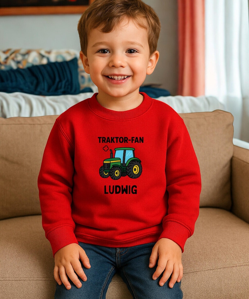 May include: A bright red long-sleeved sweatshirt featuring a graphic of a green tractor in the centre. Above the tractor, the text reads TRAKTOR-FAN, and below the tractor, the name LUDWIG is printed in bold black capital letters.