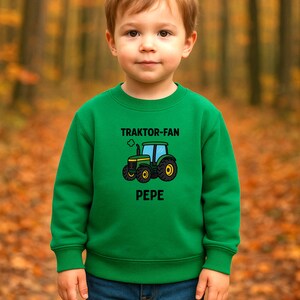 May include: A bright green long-sleeve crewneck sweatshirt featuring a graphic of a green tractor with yellow wheels. Above the tractor, the text reads TRAKTOR-FAN, and below the tractor, the name PEPE is printed in bold black capital letters.