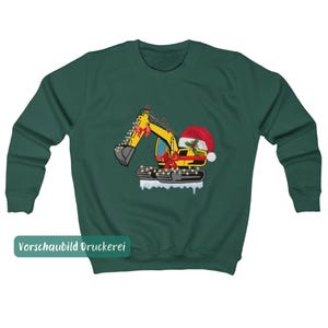 May include: A dark green crewneck sweatshirt featuring a graphic of a yellow excavator decorated with red bows, string lights, and a Santa hat. The excavator sits on a white snowy base, and the text "Vorschaubild Druckerei" appears in a green box.