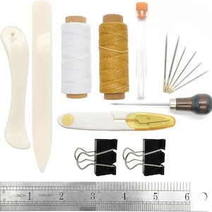 May include: A leathercrafting kit with various tools, including bone folders, spools of white and tan thread, needles, a seam ripper, and binder clips. A stainless steel ruler with inch measurements is also included.