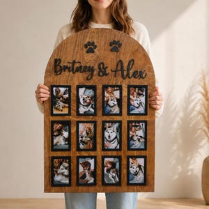 May include: An arched wooden photo collage board featuring a natural wood grain finish. The top displays two black paw print cutouts and the black script text "Britney & Alex". It includes twelve rectangular black frames for photos of dogs.