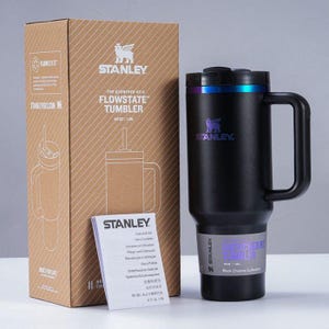 Puede incluir: Un vaso Stanley Flowstate negro con asa, tapa negra con acento azul y morado, y pajita. El vaso est&aacute; en su caja original con el logo Stanley e informaci&oacute;n del producto. Capacidad: 1,18L.