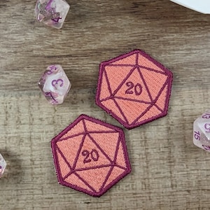 May include: Two pink and red embroidered patches shaped like a twenty-sided die, with the number "20" in the center of each die.