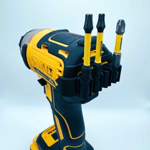 May include: A black and yellow DeWalt impact driver with three yellow and black drill bits attached. The drill bits are labeled with the DeWalt brand name. The impact driver is a power tool used for driving screws and drilling holes.