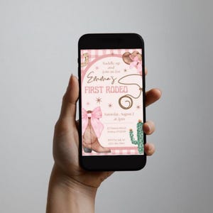 May include: A smartphone displays a rodeo-themed invitation. The design features a pink and brown color scheme with a cowboy boot, a lasso, and a cactus. The text reads "Emma's First Rodeo" with event details.