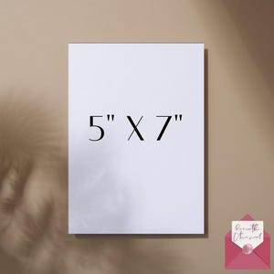 May include: A white rectangular card with the text "5" X 7" in black. The card is 5 inches by 7 inches. A pink envelope with a handwritten note is in the bottom right corner. The background is a neutral beige color.