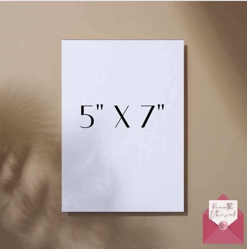 May include: A white rectangular card with the text "5" X 7" in black. The card is 5 inches by 7 inches. A pink envelope with a handwritten note is in the bottom right corner. The background is a neutral beige color.