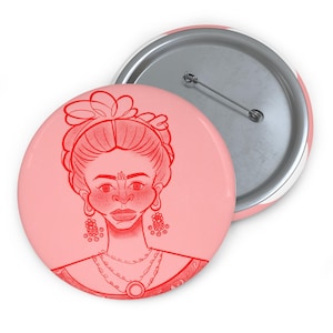 May include: Two round buttons with a red illustration of a woman with a floral hairpiece, earrings, and necklace on a pink background. The buttons have a metal pin back and a white and pink striped edge.
