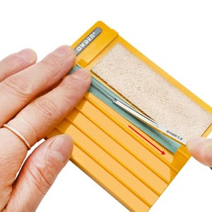 May include: A yellow plastic leather edge beveler sharpening tool with the brand name OWDEN printed on the top. The device features a rectangular beige abrasive strip and a green sharpening guide, with a metal tool marked OWDEN 5 #.
