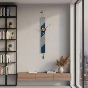 May include: A contemporary wall clock with a vertical design. The clock has a navy blue, grey, and gold colour scheme. The clock hands are black, and the clock face is gold. The clock is mounted on a white wall.