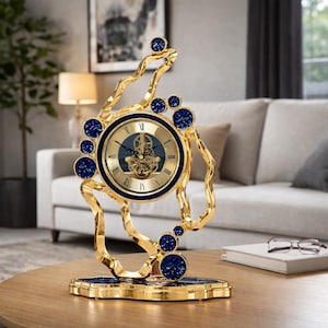May include: A decorative gold clock with a round face and Roman numerals. The clock features a blue bezel and is embellished with blue gemstones. The clock sits on a gold base and has an ornate, flowing design.