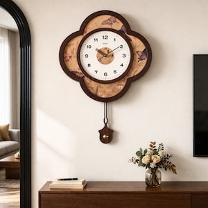 May include: A decorative wall clock with a unique cloverleaf shape. The clock face is white with black numerals and hands. The outer frame is dark brown, with a butterfly and floral pattern. A pendulum hangs below the clock.