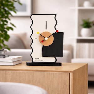 May include: Abstract art deco style clock with a black base and frame. The clock face features a cream-colored background with a black wavy edge, a tan circle, and a black square. The clock hands have red and yellow accents. The clock has the text "U5100M".