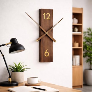 May include: A rectangular wooden wall clock with gold numerals at the top and bottom, and gold-tipped hands. The clock is mounted on a white wall. The clock is part of a home decor theme.
