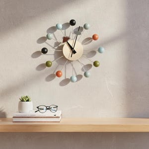 Może przedstawiać: Biały ceramiczny kubek z czarnym uchwytem i napisem "But First, Coffee" czarną, pogrubioną czcionką. Kubek stoi na drewnianej powierzchni. Kubek ma około 10 cm wysokości.