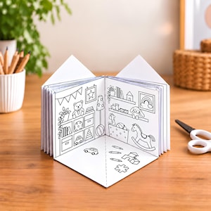 Puede incluir: Un libro desplegable de papel blanco con ilustraciones de líneas en blanco y negro de una habitación llena de juguetes. Las páginas abiertas muestran estantes con un oso de peluche, un caballito de madera y varios juguetes, además de un coche.