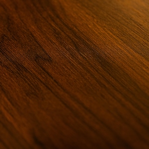 May include: Close-up of a richly textured, dark brown wooden surface. The wood grain is visible, with a diagonal pattern and a gradient from light to dark. The surface has a warm, inviting tone, suitable for furniture or decor.