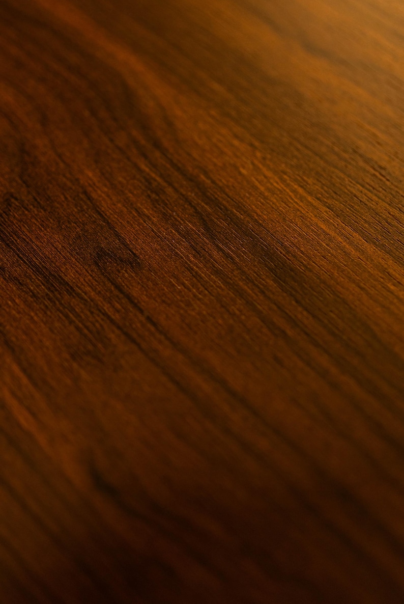 May include: Close-up of a richly textured, dark brown wooden surface. The wood grain is visible, with a diagonal pattern and a gradient from light to dark. The surface has a warm, inviting tone, suitable for furniture or decor.