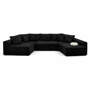 K&ouml;nnte beinhalten: Ein gro&szlig;es, schwarzes Ecksofa in U-Form mit mehreren Kissen. Das Sofa hat eine Cordstruktur. Ein kleiner, wei&szlig;er Zierk&uuml;rbis liegt auf dem Ottoman. Das Sofa ist f&uuml;r ein Wohnzimmer konzipiert.