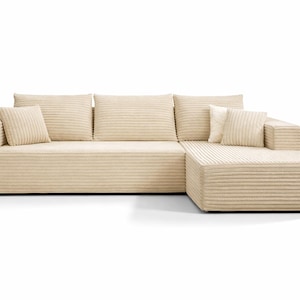 K&ouml;nnte beinhalten: Beiges Ecksofa mit Cordstruktur. Das Sofa hat eine Chaiselongue auf der rechten Seite und enth&auml;lt mehrere passende quadratische und rechteckige Kissen. Die neutrale Farbe und das schlichte Design passen zu verschiedenen Einrichtungsstilen.
