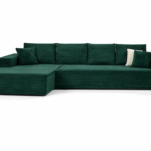 K&ouml;nnte beinhalten: Ein gro&szlig;es, smaragdgr&uuml;nes Ecksofa mit Cordstruktur. Das Sofa hat eine Chaiselongue auf der linken Seite und mehrere passende Kissen. Ein wei&szlig;es Kissen sorgt f&uuml;r Kontrast. Die M&ouml;bel stehen vor einem wei&szlig;en Hintergrund.