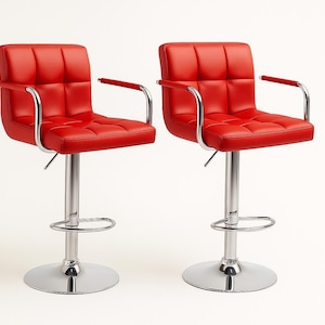 May include: Two red, adjustable height bar stools with chrome-finished bases and armrests. The seats and backs are square-stitched. The stools have a footrest and a round base.