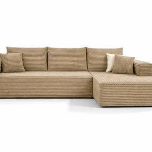 K&ouml;nnte beinhalten: Ein modernes, beiges Cord-Ecksofa mit einer Chaiselongue. Das Sofa hat ein niedriges Profil, eine breite Armlehne und mehrere passende quadratische Wurfkissen. Der Cordstoff hat eine gerippte Textur. Das Sofa steht vor einem wei&szlig;en Hintergrund.