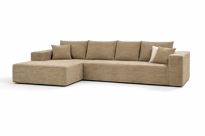 K&ouml;nnte beinhalten: Beiges Cord-Ecksofa mit einer Chaiselongue auf der linken Seite. Das Sofa hat ein niedriges Profil und enth&auml;lt mehrere passende Kissen. Der Cordstoff hat eine gerippte Textur.