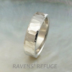 May include: A silver hammered wedding band with a smooth, polished interior. The band is thick and has a slightly rounded profile.