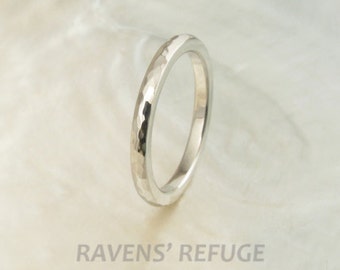 May include: A simple silver band ring with a hammered texture. The ring is shown on a white background.